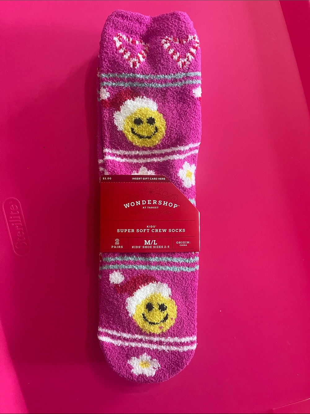 Wondershop Pink Fuzzy Crew Socks with Yellow Smiley Faces wearing a Santa Hat